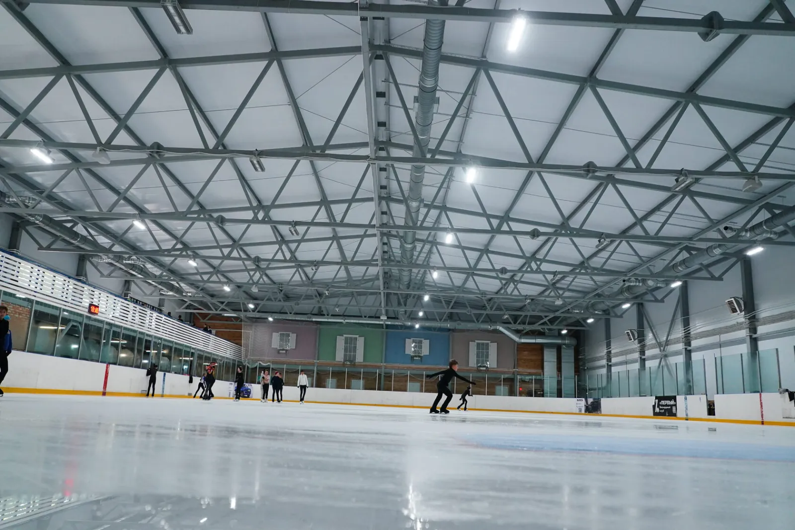 The 55 by 25 metre ice field of the Khrustalny Konek rink with skaters at a distance — Khrustalny Konek Ice Arena Voronezh