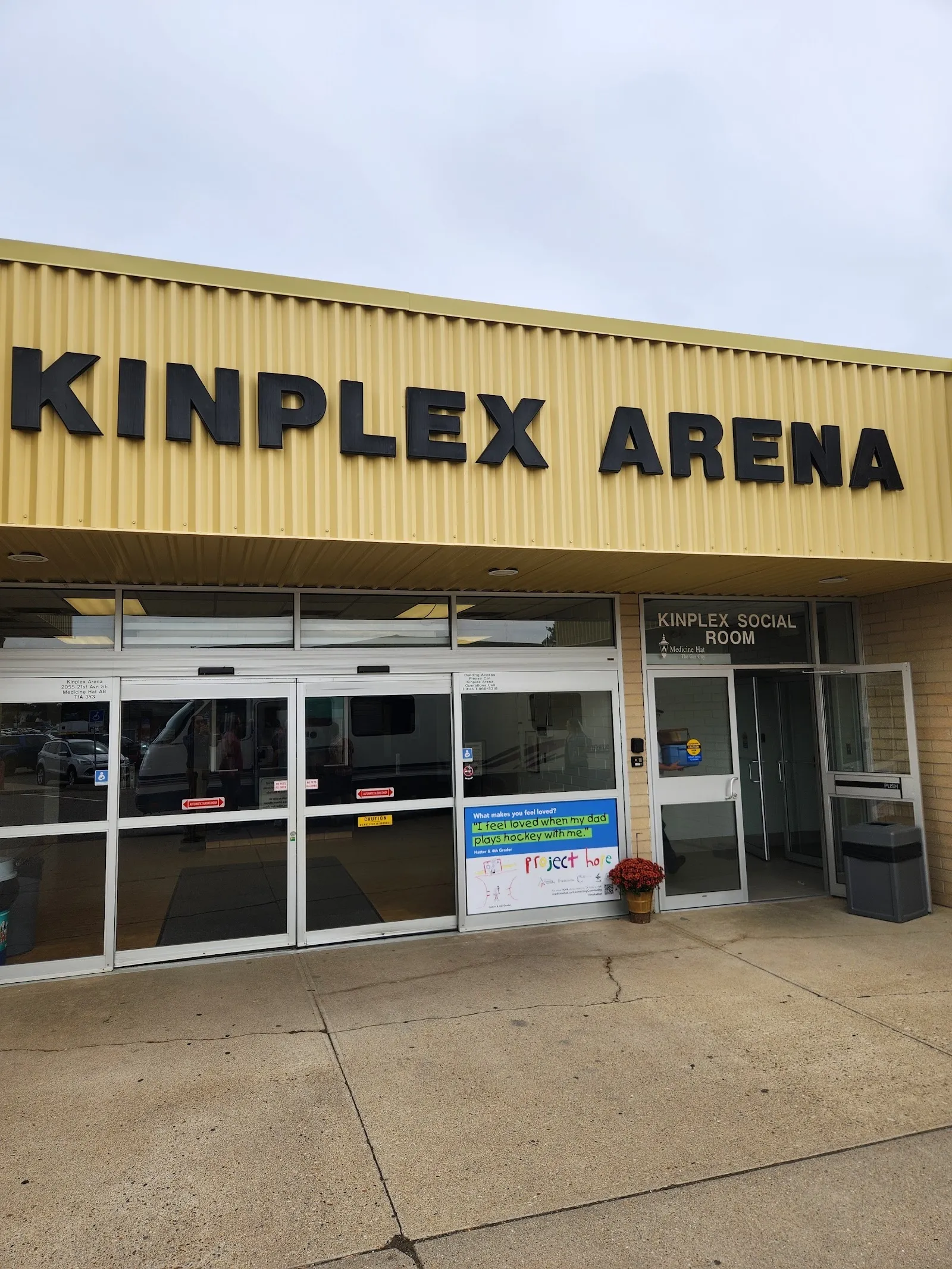 The yellow-brick front of the Kinplex Arena with its name in black letters above a glazed double entrance, seen in daylight. — Kinplex