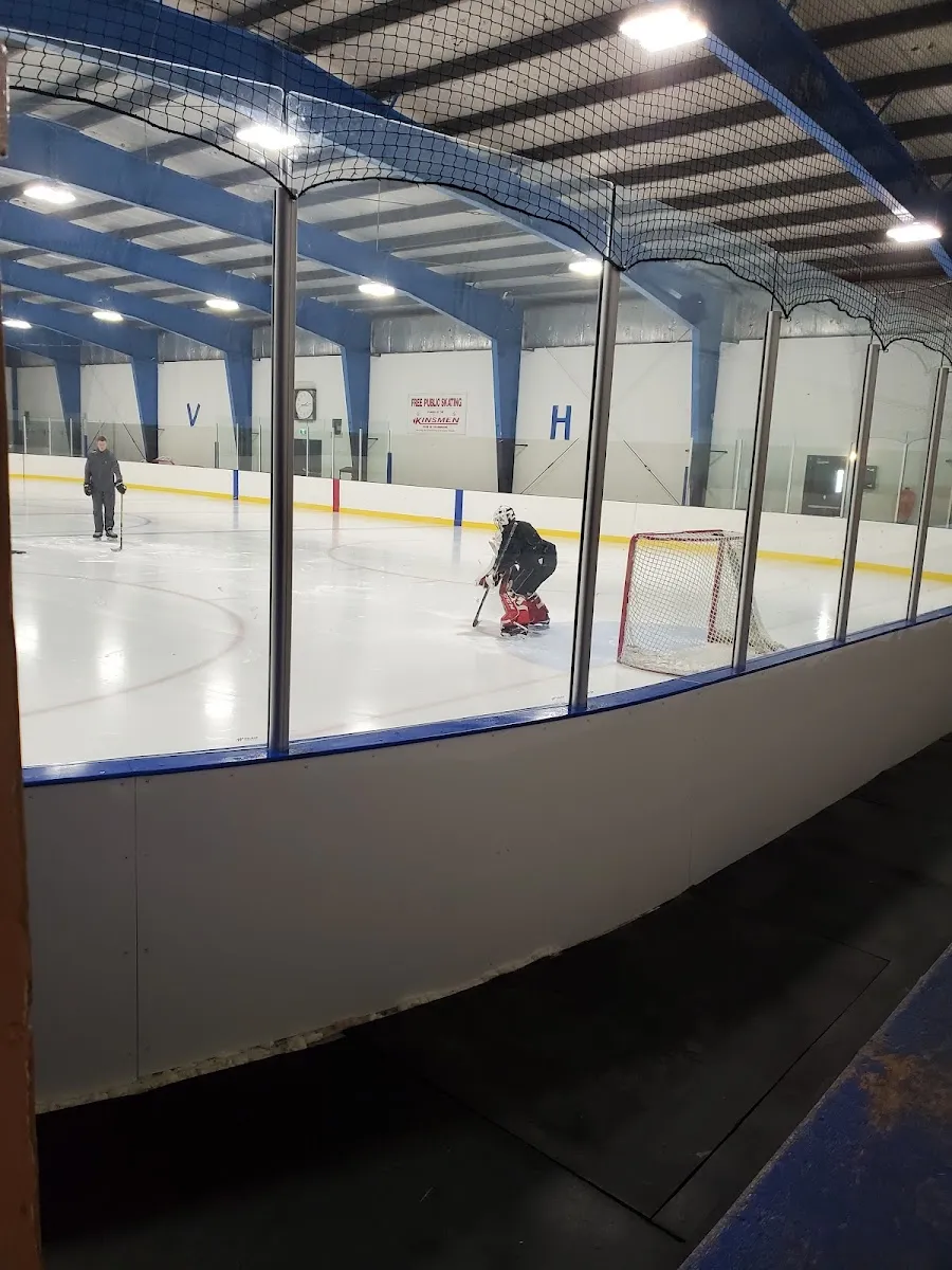 Kinsmen Arena ice behind the glass, with the free public skating sign on the far wall — Kinsmen Arena