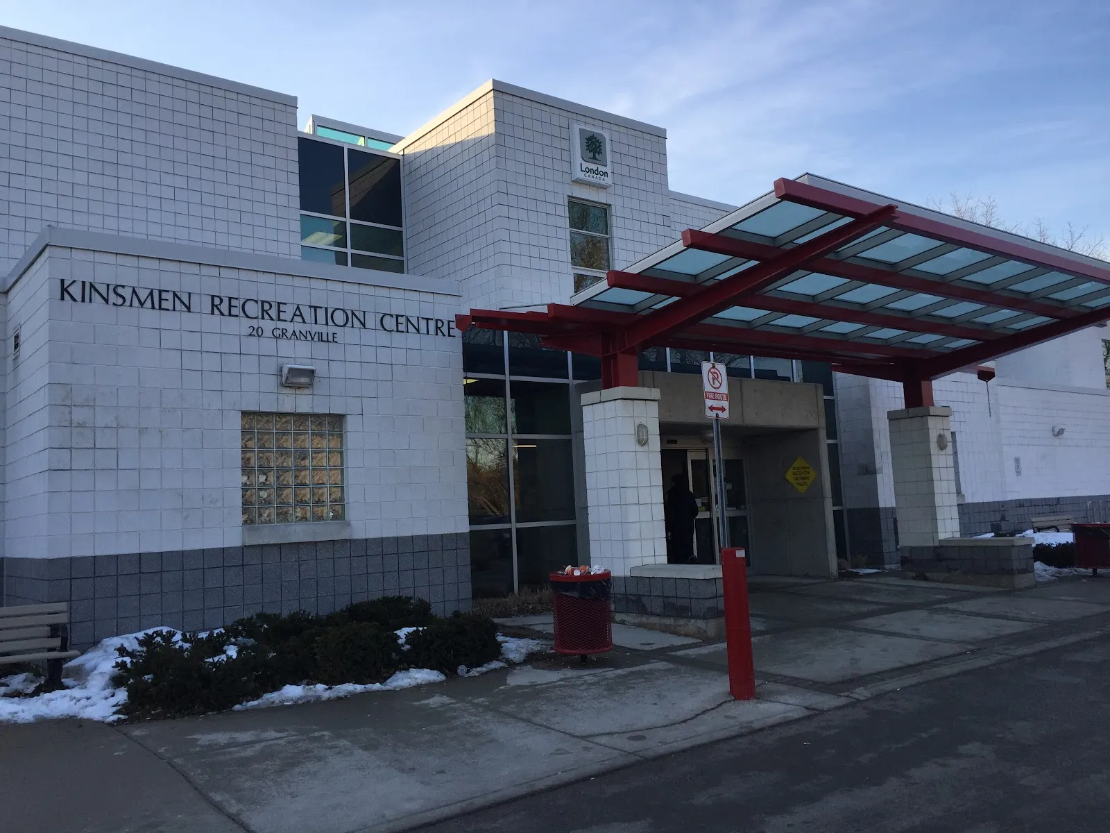The entrance to the Kinsmen Recreation Centre, 20 Granville, with its name on the wall and a red-framed glass canopy. — Kinsmen Arena (London)