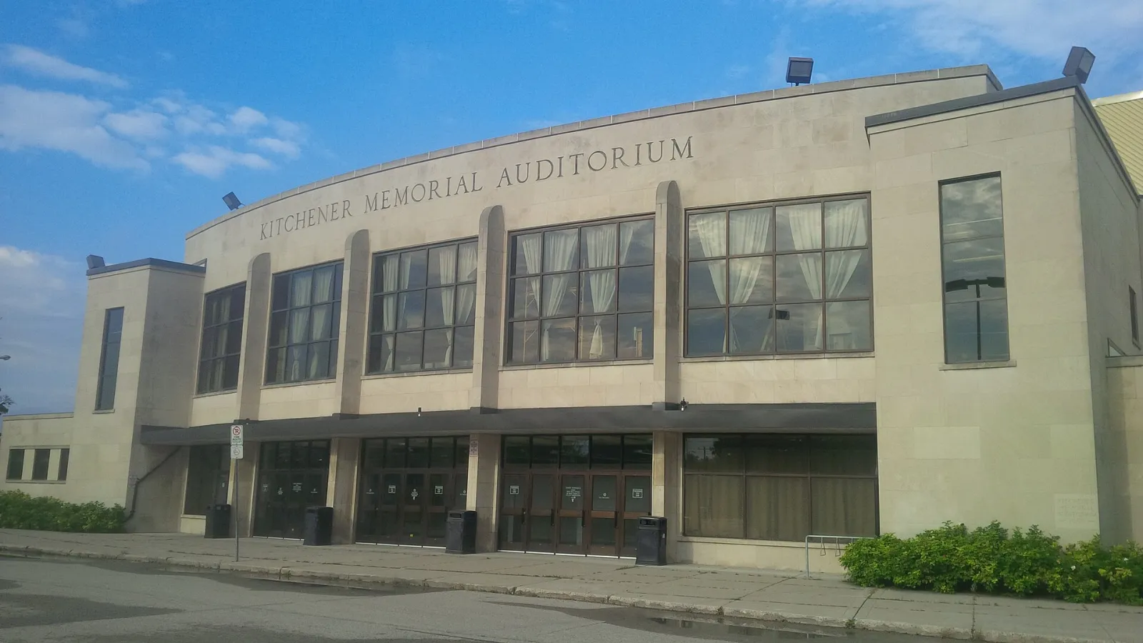 El frente de piedra del Kitchener Memorial Auditorium Complex, el edificio que alberga los estadios Kiwanis y Kinsmen, con el nombre del edificio en el muro superior. — Kiwanis Arena (The Aud)