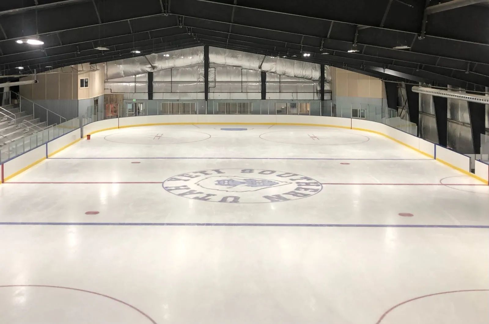 The empty ice sheet inside KJ's Ice Barn in Enoch, with the boards, stands and the centre-ice logo — KJ's Ice Barn