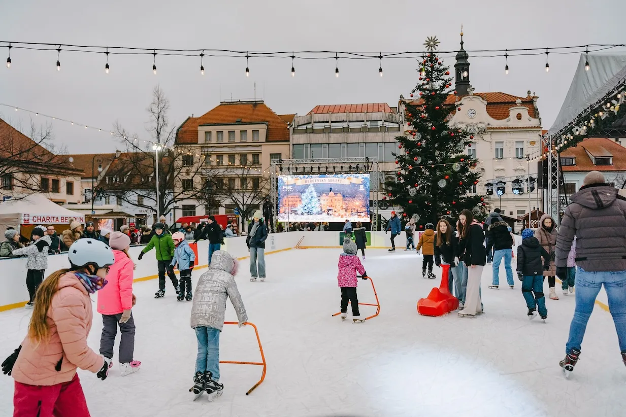 Bruslaři na kluzišti Kluziště Beroun na Husově náměstí, za nimi radnice a vánoční strom – Kluziště Beroun (Husovo náměstí)
