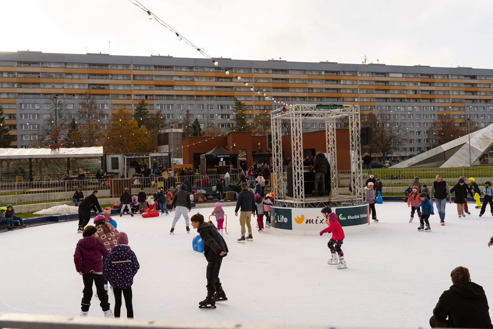 Skaters on the round Kluziště Střížkov rink in Park přátelství with the DJ stage and the housing blocks behind — Kluziště Střížkov (Park přátelství)