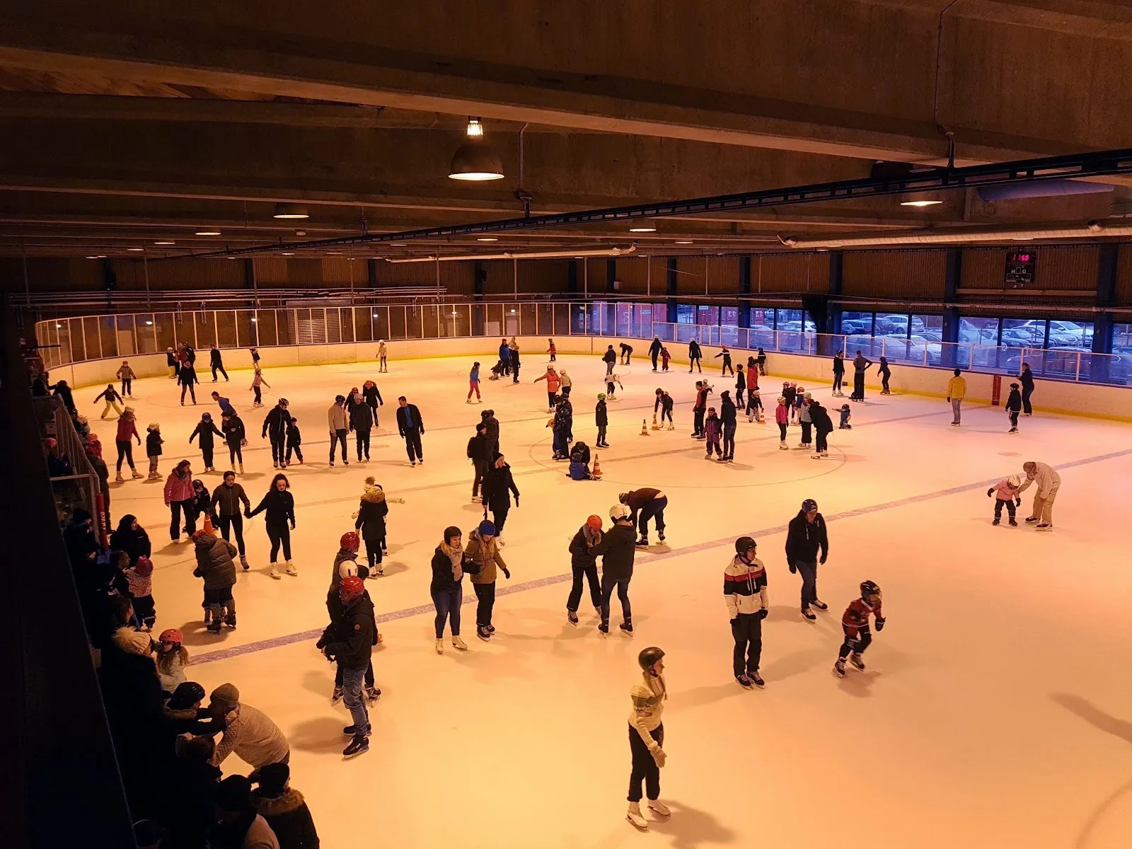 Skaters filling the ice at Kockum Fritid ishall in Malmö during a public session, lit in warm light under the hall roof. — Kockum Fritid ishall