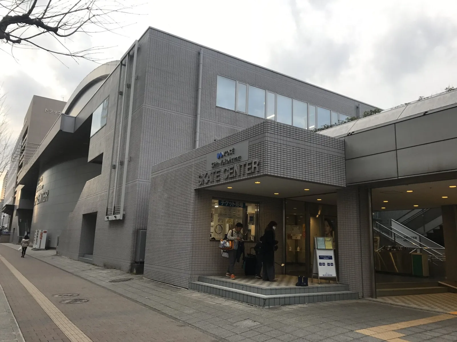 通りに面した、KOSÉ新横浜スケートセンターのタイル張りの入口 — KOSÉ Shin-Yokohama Skate Center