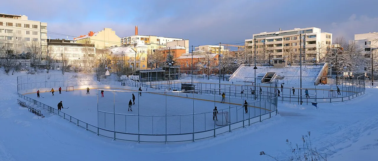 Panoramabild över Koulukatu-banan i Tammerfors på vintern, med skridskoåkare på isen – Koulukadun kenttä ja tekojäärata