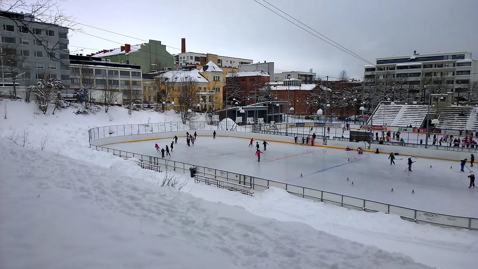 Skridskoåkare på konstisbanan vid Koulukatu i Tammerfors på vintern – Koulukadun kenttä ja tekojäärata