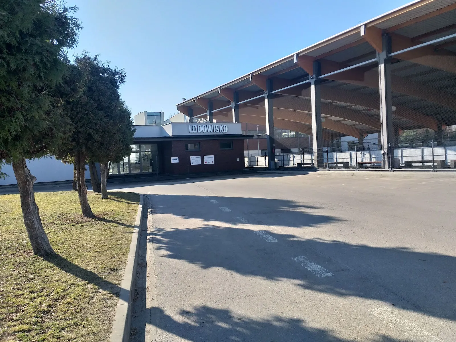 The covered rink in Garwolin, a timber-framed roof over the ice with the Lodowisko sign above the entrance — Kryte Lodowisko CSiK Garwolin