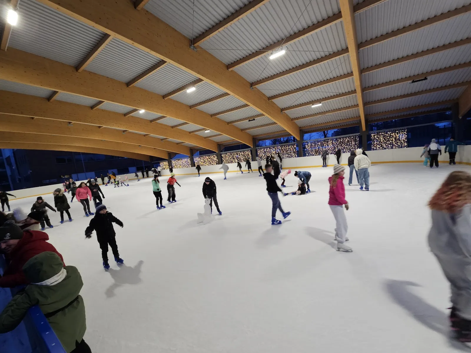 A busy public session under the timber roof of the covered rink in Garwolin — Kryte Lodowisko CSiK Garwolin