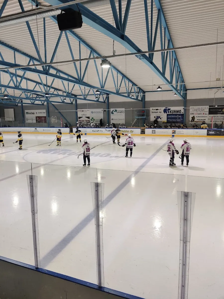 Young skaters practising along the near boards of the Kuhmo ice hall under the arched steel roof. – Kuhmon jäähalli