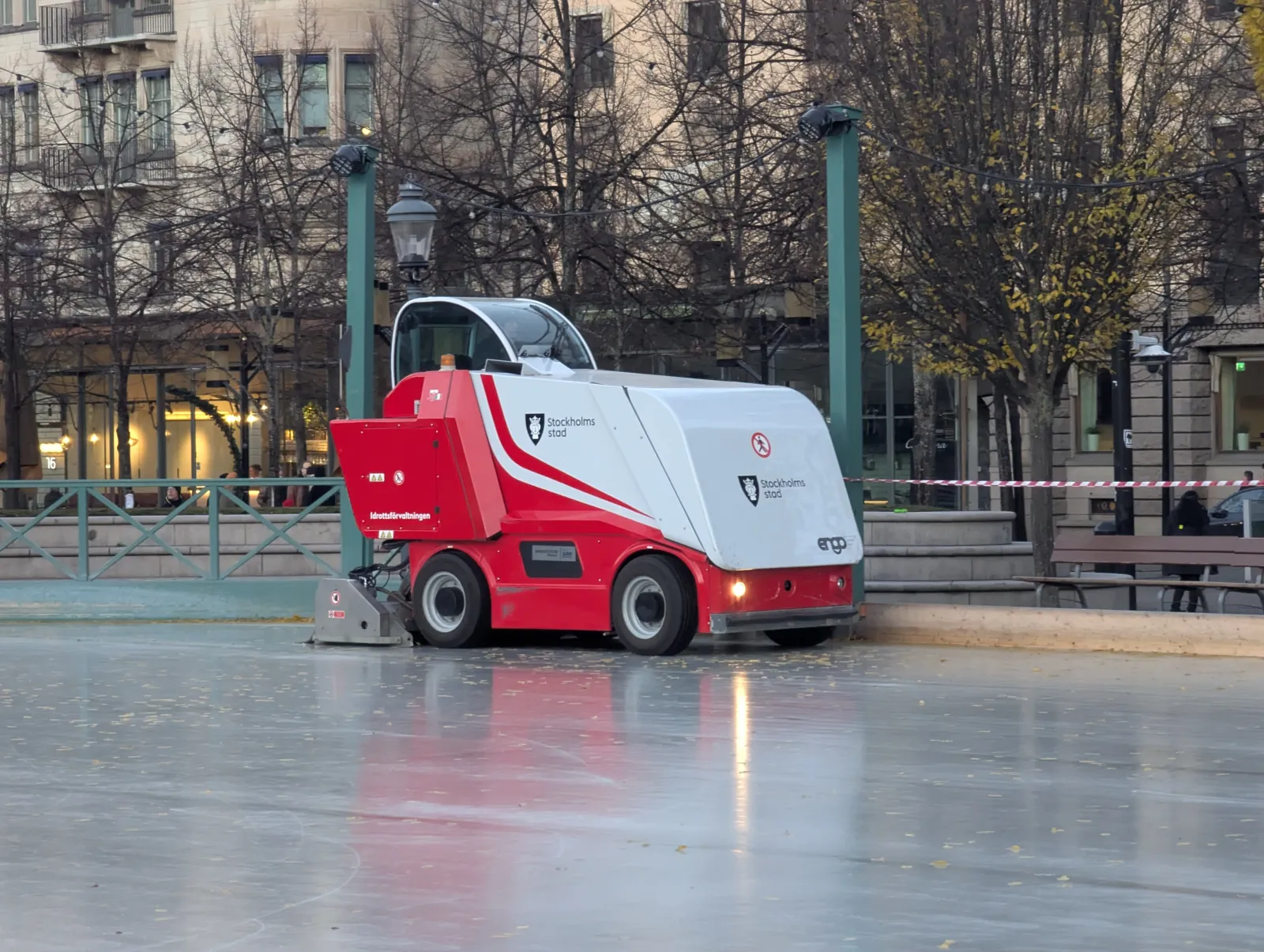 The ice resurfacer of Stockholms stad working the ice at Kungsträdgårdens isbana before the season, with the park's promenade and trees behind — Kungsträdgårdens isbana