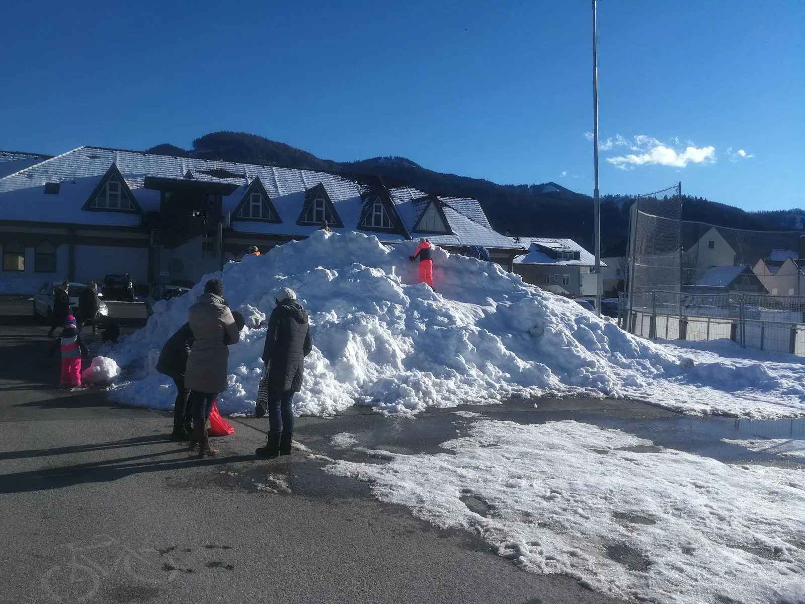 The clubhouse building beside the Langenwang artificial ice rink in the Mürz valley, with the hills behind – Kunsteisanlage Langenwang