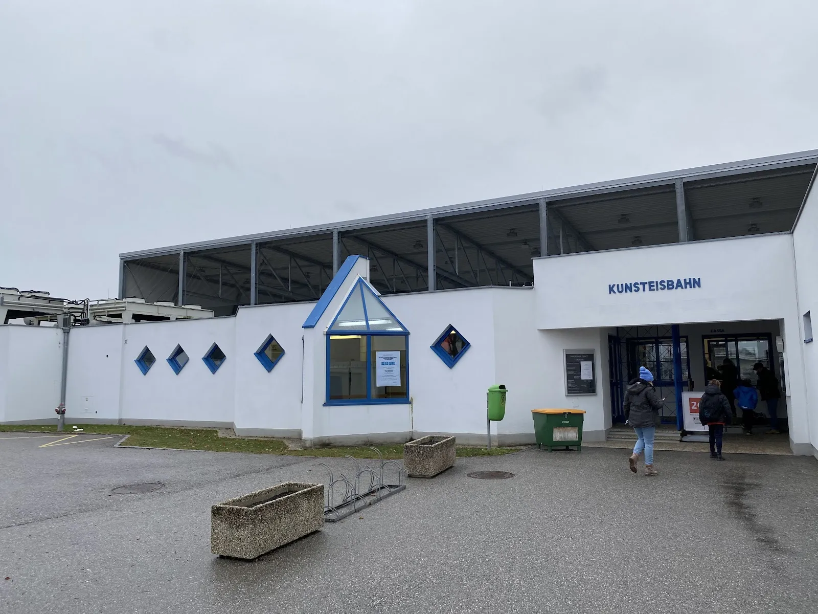 The entrance of the Kunsteisbahn in Ternitz, a white building with diamond windows and the KUNSTEISBAHN sign — Kunsteisarena Ternitz