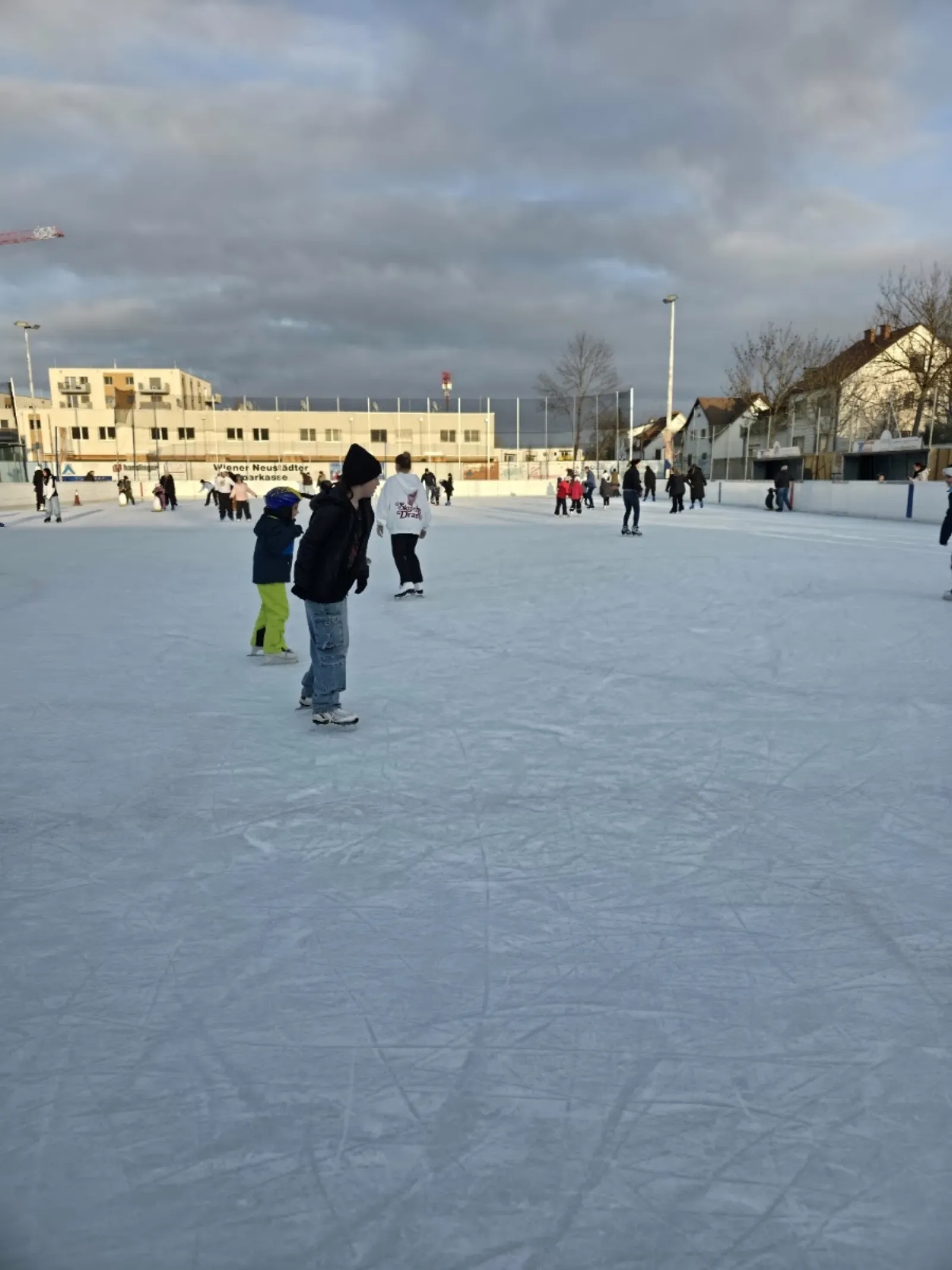 The outdoor ice rink with skaters at a distance and the Wiener Neustadt Sparkasse banner along the boards (Google Maps listing photo) — Friedrich Fellerer Kunsteisbahn