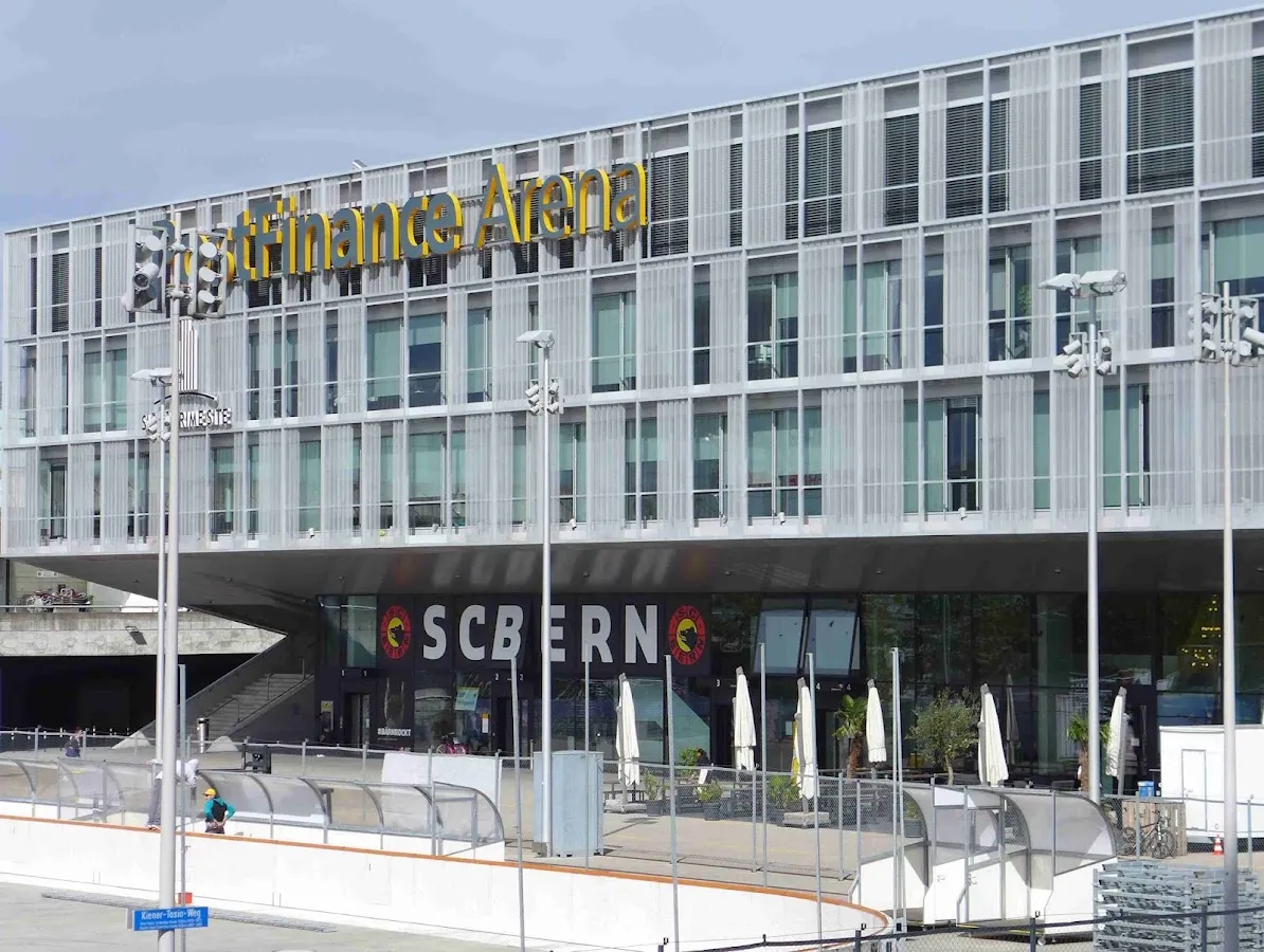 Die Glasfassade der PostFinance-Arena in Bern, davor der Rand des Freiluft-Eisfelds – Kunsteisbahn PostFinance-Arena