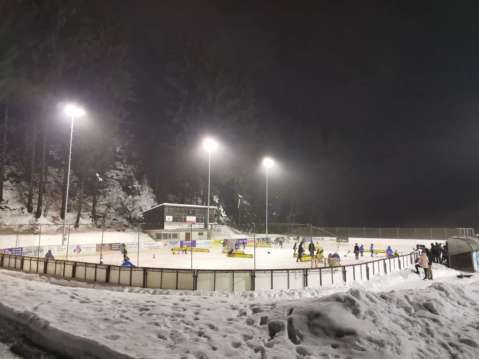 The floodlit outdoor ice rink KEB Schiers at night, skaters at a distance — Kunsteisbahn Schiers (KEB)
