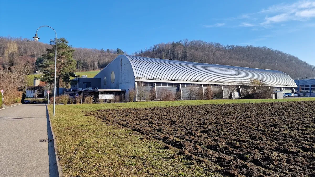 Die gewölbte Halle der Kunsteisbahn Sissach vom benachbarten Feld aus gesehen – Kunsteisbahn Sissach