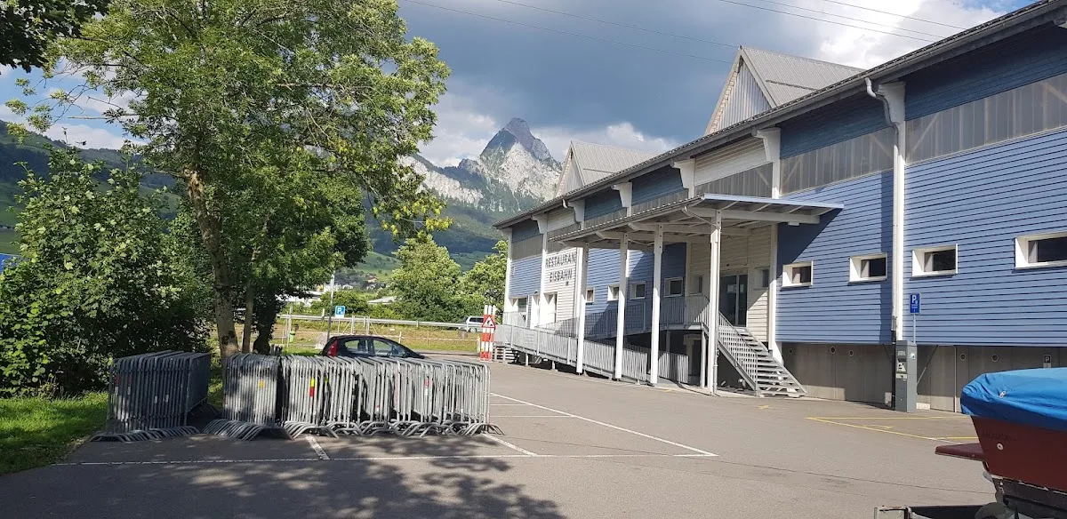 Das Gebäude der Kunsteisbahn Zingel in Seewen mit den Mythen dahinter – Kunsteisbahn Zingel