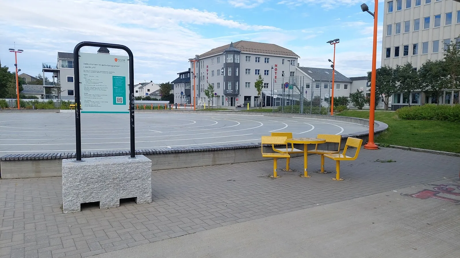 Isflaten til Kvartal 99 på parkeringstaket om sommeren, uten is, ved siden av informasjonstavlen — Kvartal 99 isbane