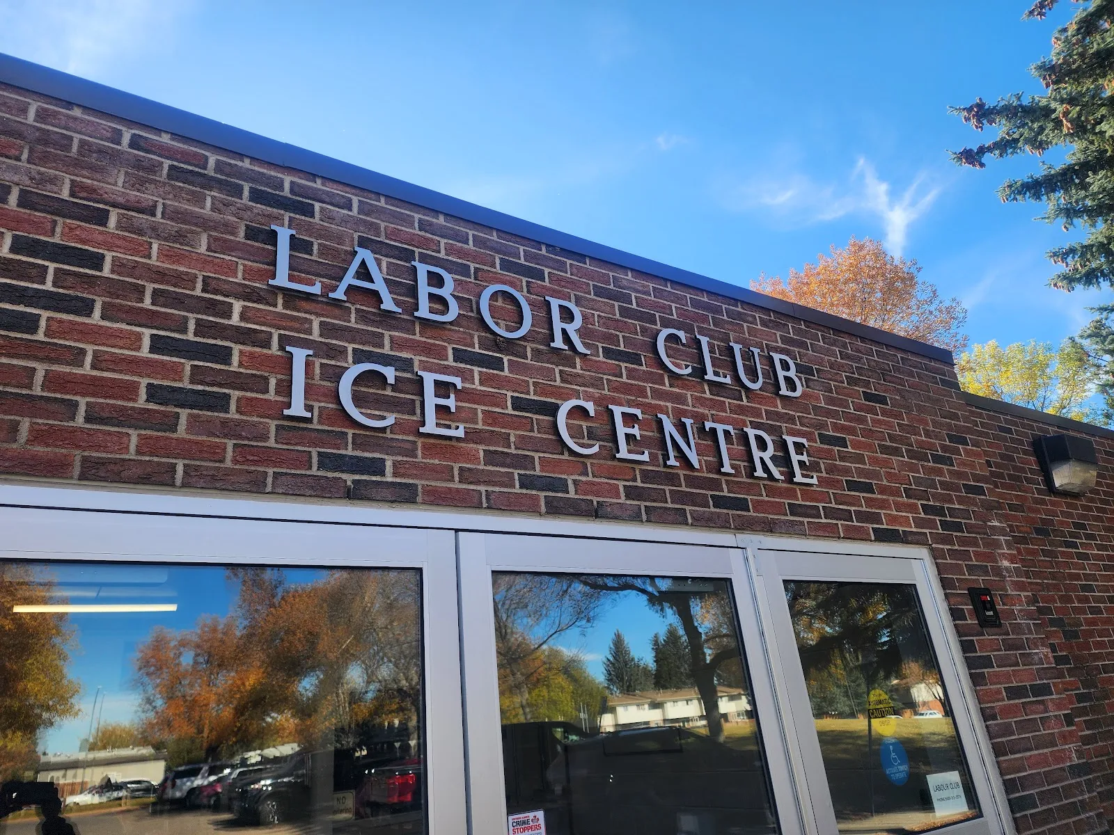 Raised LABOR CLUB ICE CENTRE lettering on the brick facade above glass entry doors. — Labour Club Ice Centre