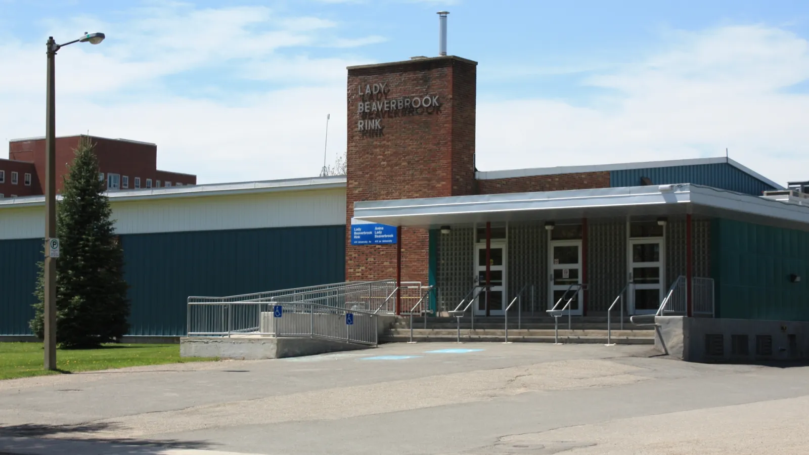 The brick tower and blue-trimmed entrance of the Lady Beaverbrook Rink with its name on the tower. — Lady Beaverbrook Rink