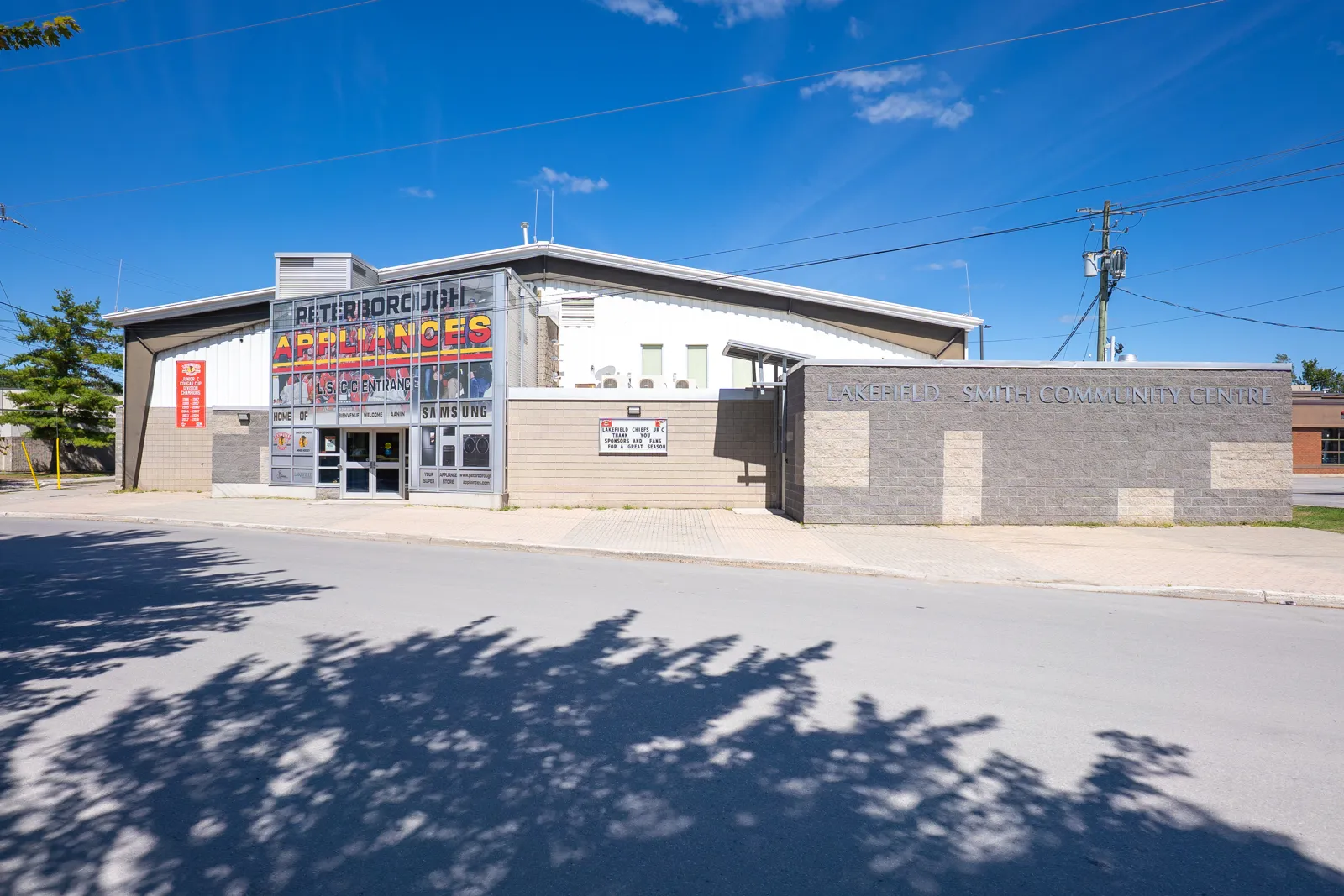 The arena front on Concession Street, a glass entrance block beside the long brick wall lettered Lakefield-Smith Community Centre. — Lakefield-Smith Community Centre