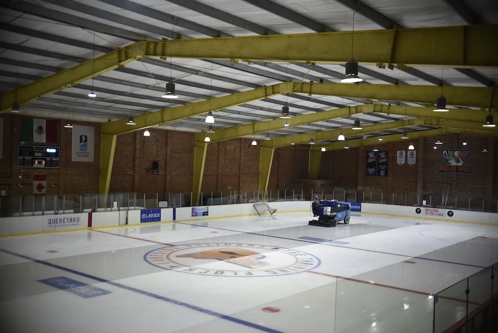 The Lakeside Icepark rink under its steel-framed roof, a hockey crest at centre ice and the glass and boards around the sheet. — Lakeside Ice Park