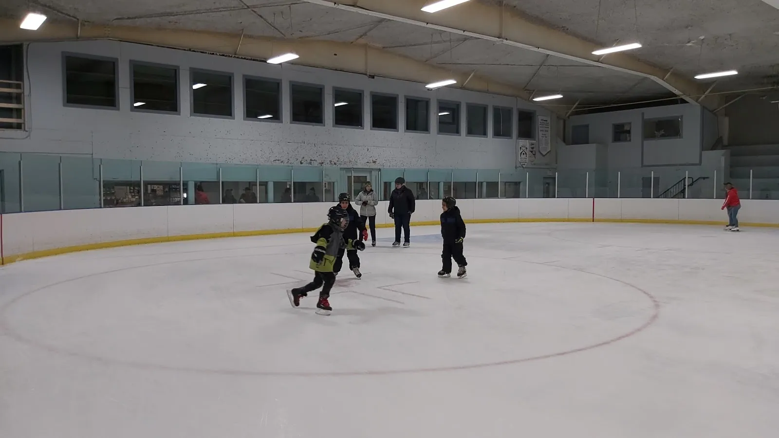 Skaters on the ice at a public skate in the Lanark arena, under the curved roof trusses — Lanark & District Community Centre