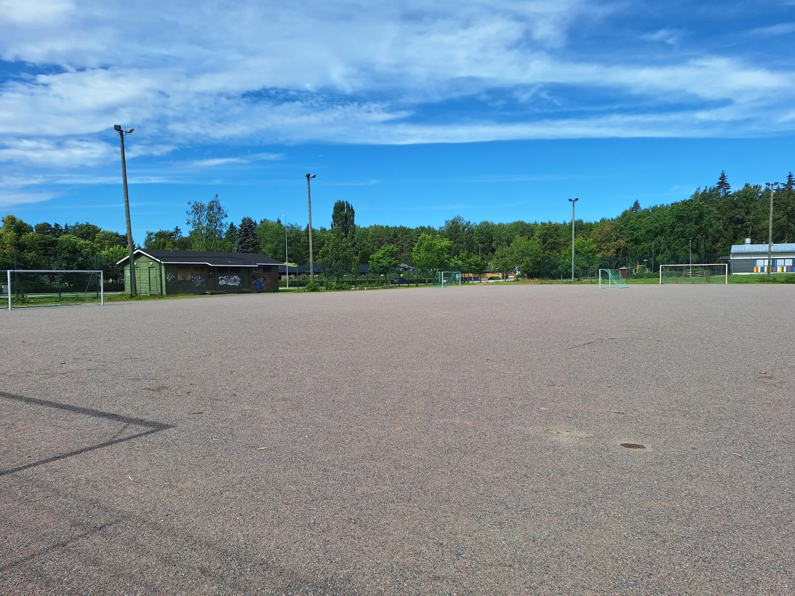 The Lauklähteen field in summer, a ball field with a gravel (stone-dust) surface with goals; the City of Turku freezes its fields into skating fields in winter. — Lauklähteen luistelukenttä