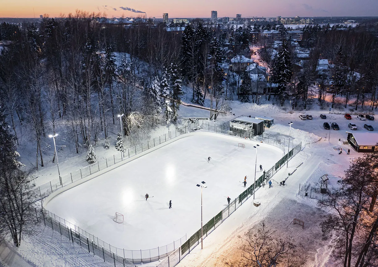 Ilmakuva Lauttasaaren liikuntapuiston tekojääkaukalosta, jossa pelataan jääkiekkoa. – Lauttasaaren liikuntapuisto – tekojääkaukalo
