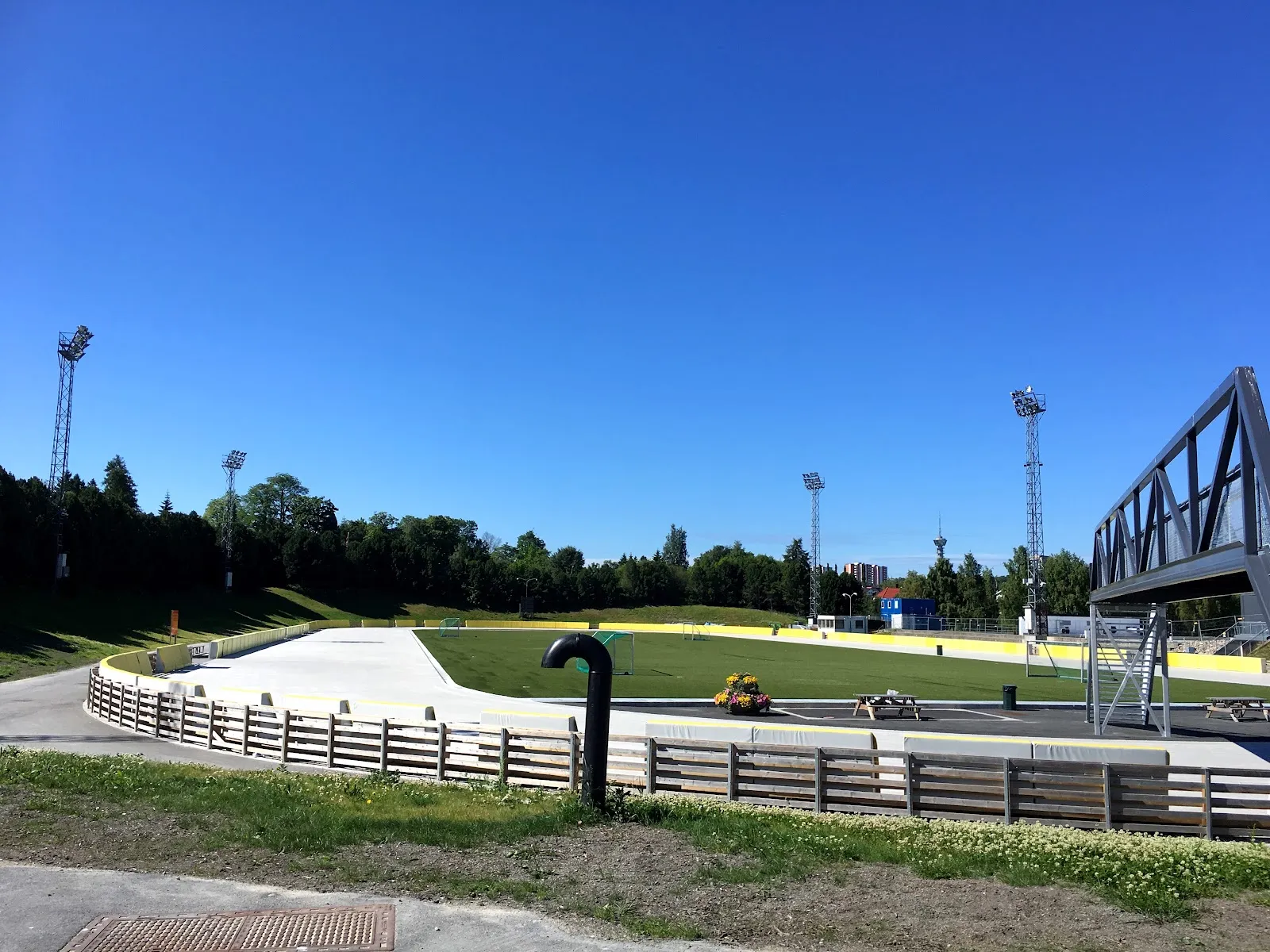 The Leangen kunstisbane oval in summer, with the floodlight masts and the footbridge over the track — Leangen kunstisbane