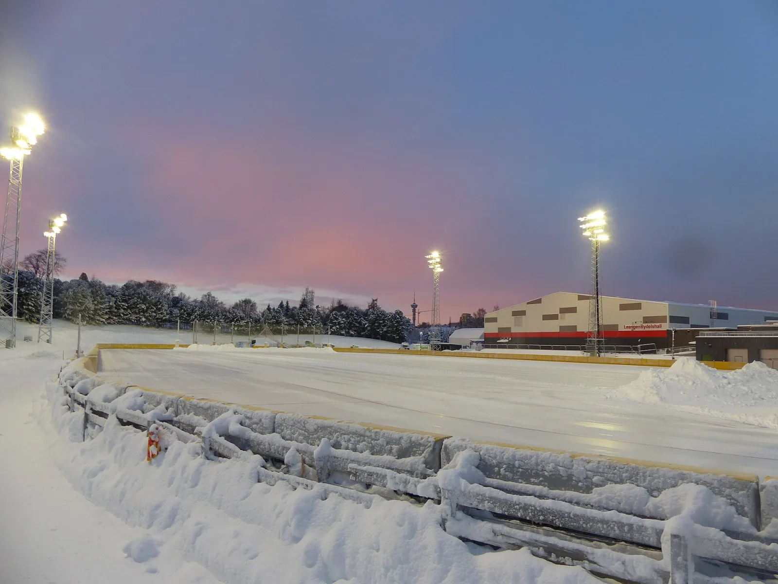 The artificial-ice speed-skating track at Leangen under floodlights, with Leangen bydelshall behind — Leangen kunstisbane