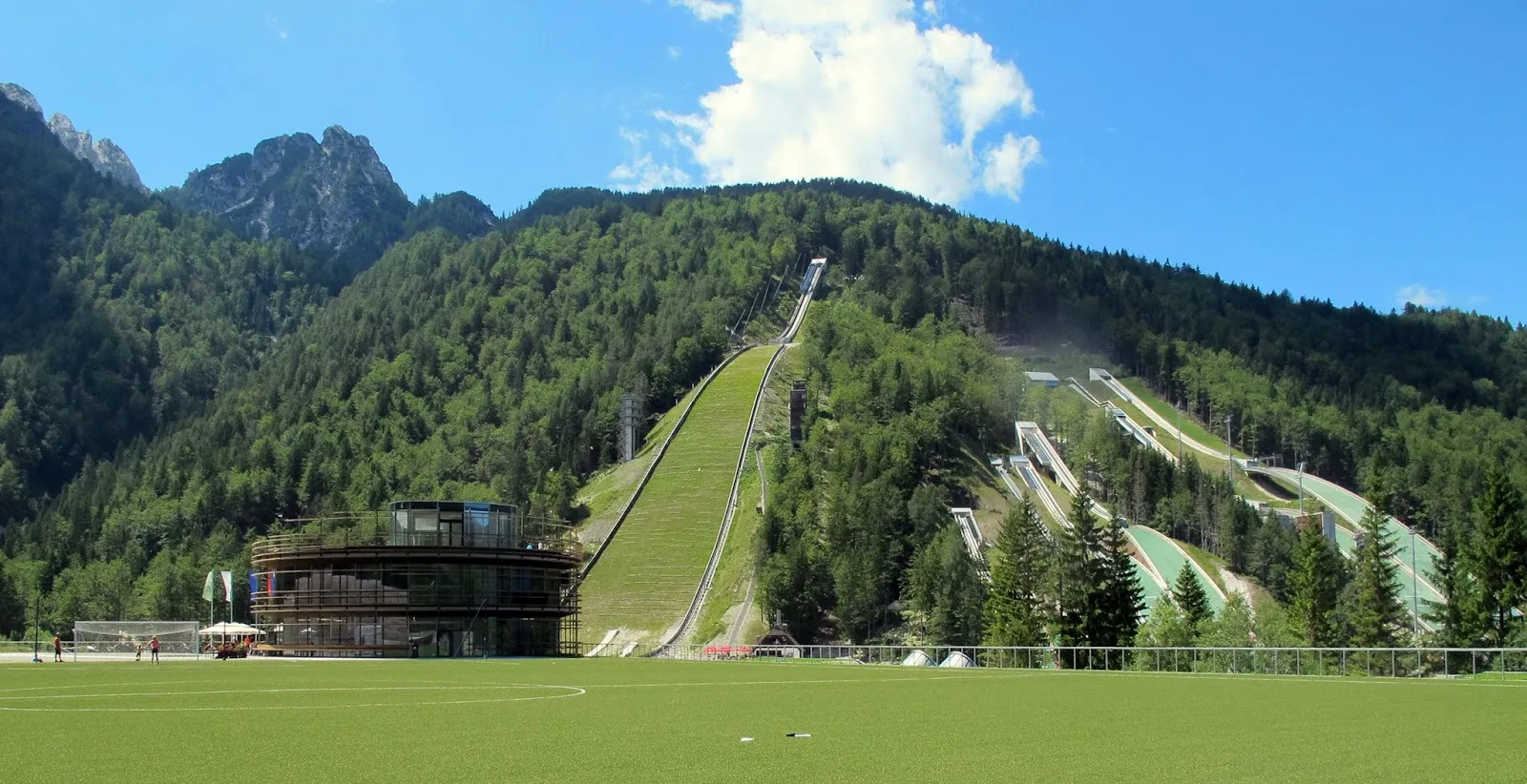The Planica Nordic Centre building and its ski jumps, where the Ledena Planica ice rink is set up in winter — Ledena Planica Ice Rink