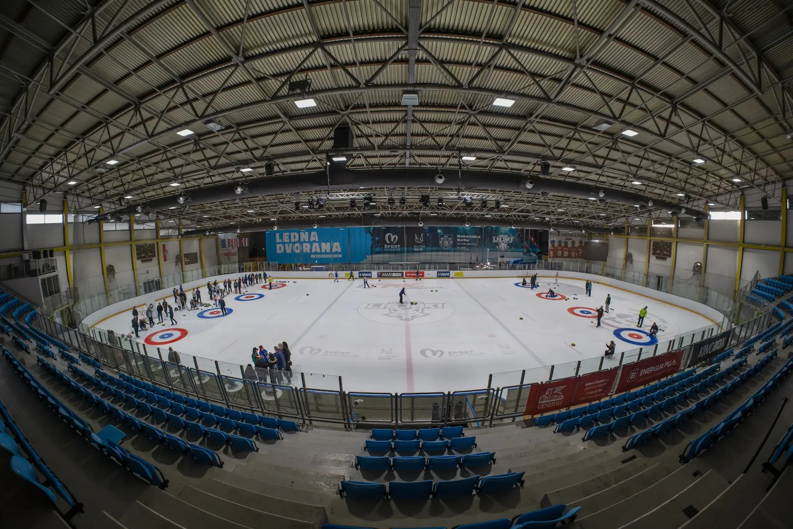 The ice surface and blue stands of Ledna dvorana in Maribor, laid out with curling targets — Ledna dvorana Maribor