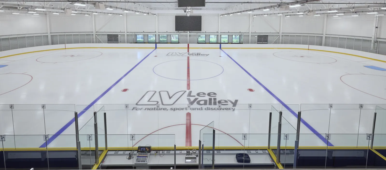 One of the two Olympic-size rinks, empty and freshly surfaced, with the Lee Valley logo at centre ice and scoreboards along the far wall. — Lee Valley Ice Centre