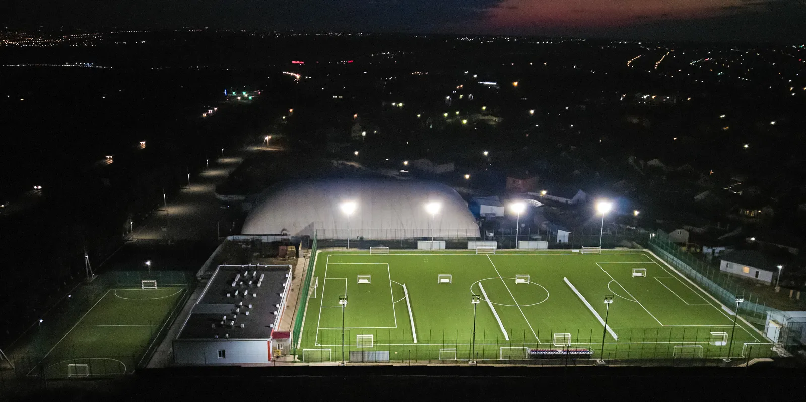 The dome of the Lider rink beside the football pitch, seen from the air at night — Lider Ice Rink Mikhaylovsk