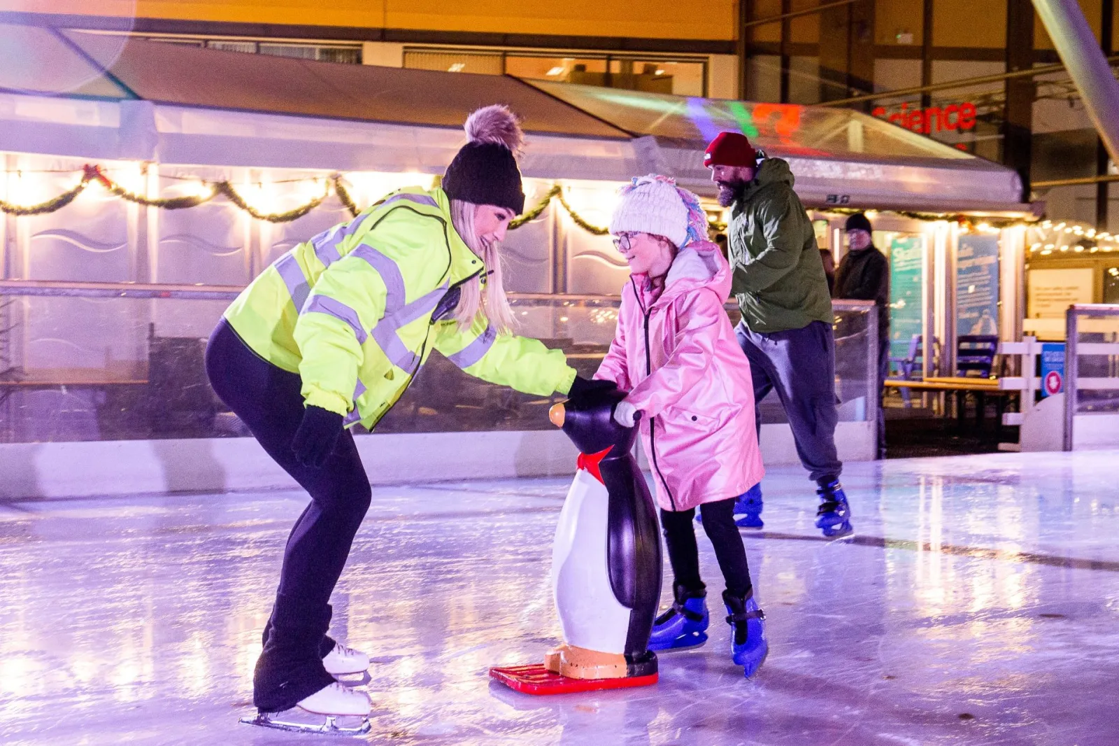 A rink steward helping a young skater with a penguin skating aid on the ice (the centre's photo, published on the Get into Newcastle page) — Life Science Centre Ice Rink (Newcastle)