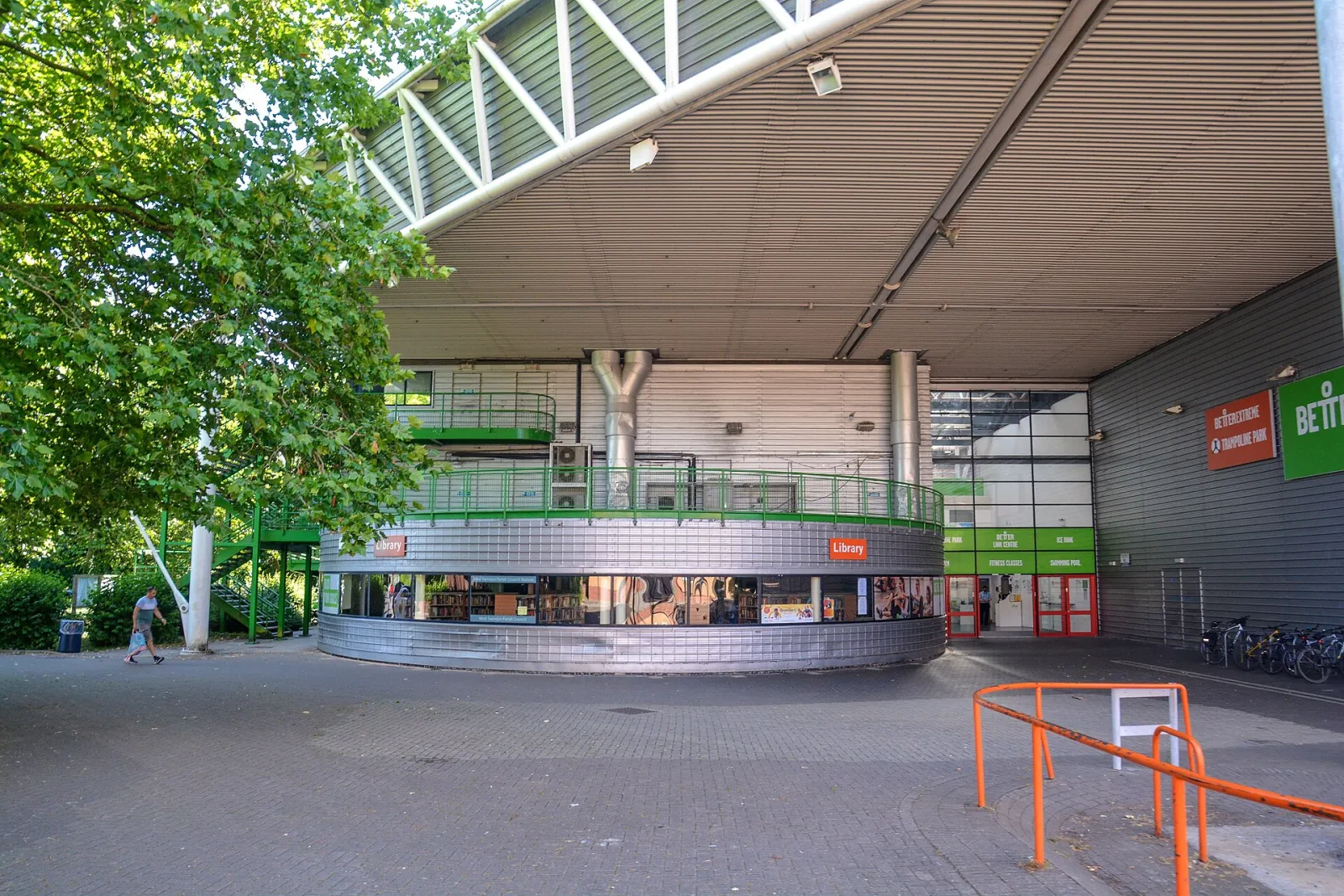 The Link Centre's main entrance under its deep overhanging roof, with the round library wing in front and the Better signs beside the doors. — Link Centre