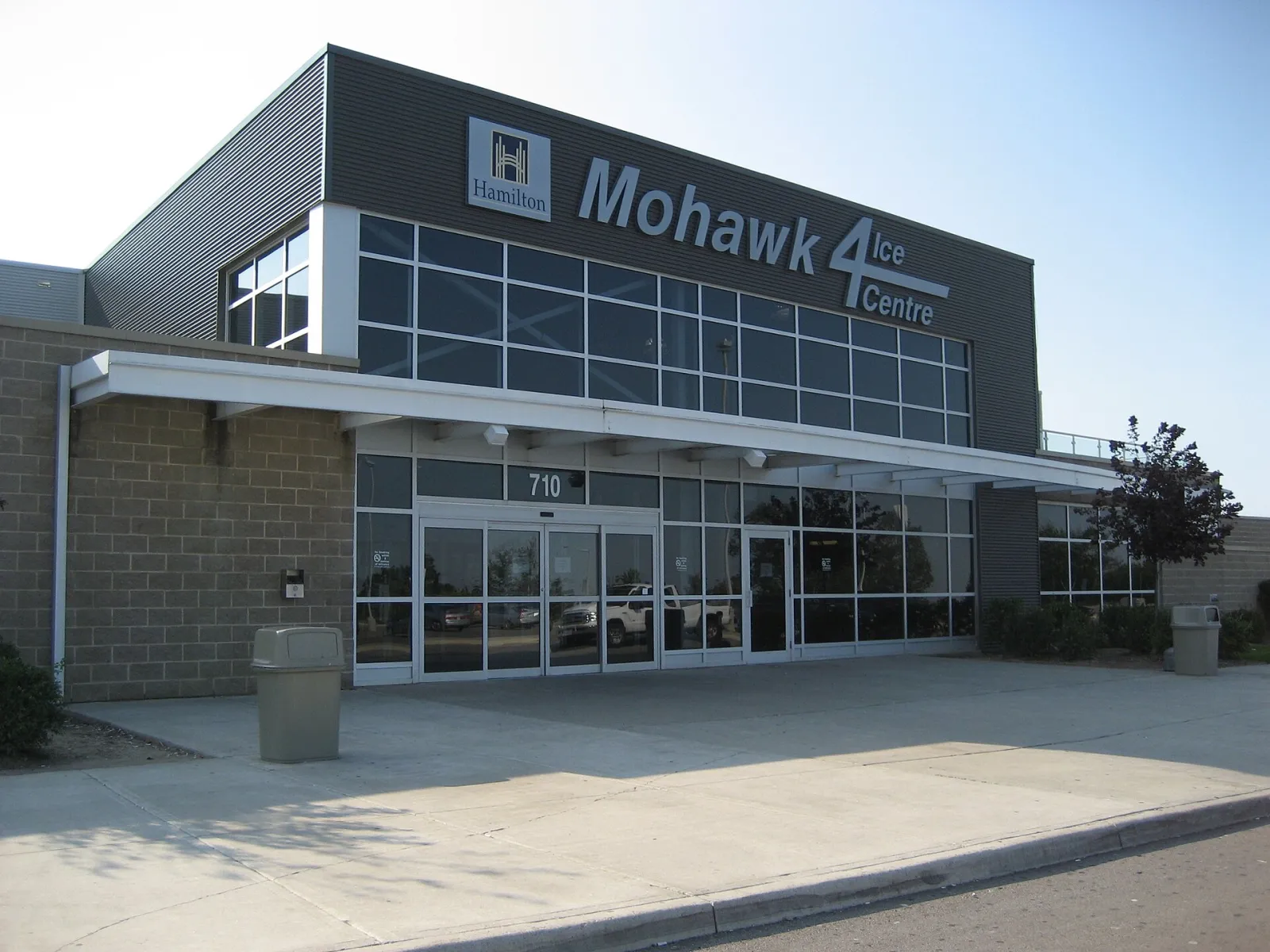 La entrada de vidrio del centro bajo una marquesina oscura, fotografiada cuando aún llevaba el nombre de Mohawk 4 Ice Centre. — LIUNA 4 Ice Centre
