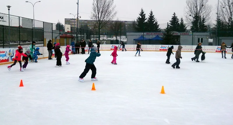 Public skating on the open-air Biały Orlik rink in Łomża, with skaters spread across the ice between orange cones and a fence behind. — Lodowisko Biały Orlik (Łomża)