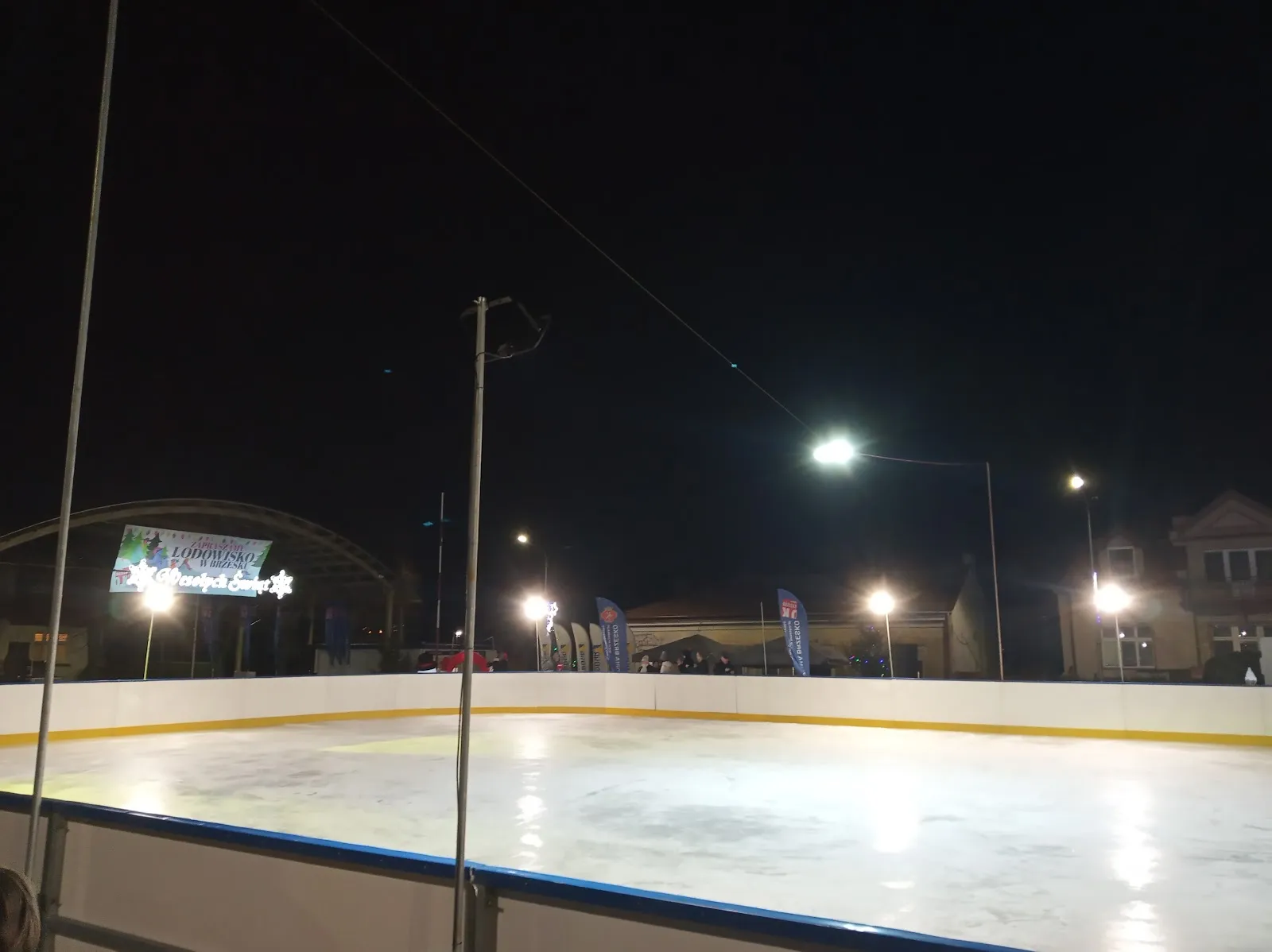 The ice of the Brzesko rink on Plac Kazimierza Wielkiego at night, with its boards and lights — Lodowisko BOSiR Brzesko