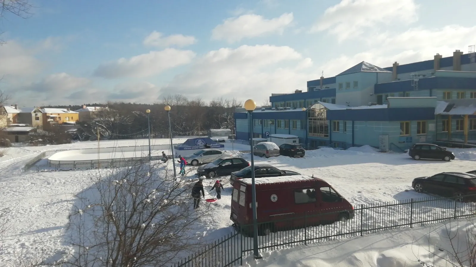 The CSiR sports-centre building and its car park beside the Augustów ice rink in winter — Lodowisko CSiR Augustów
