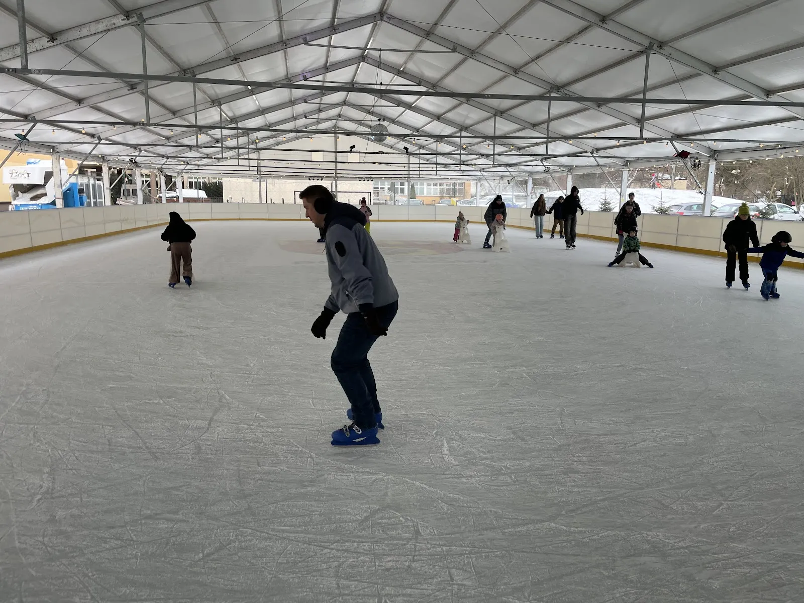 Skaters on the ice under the white canopy of the Pruszków municipal rink — Lodowisko Miejskie Pruszków