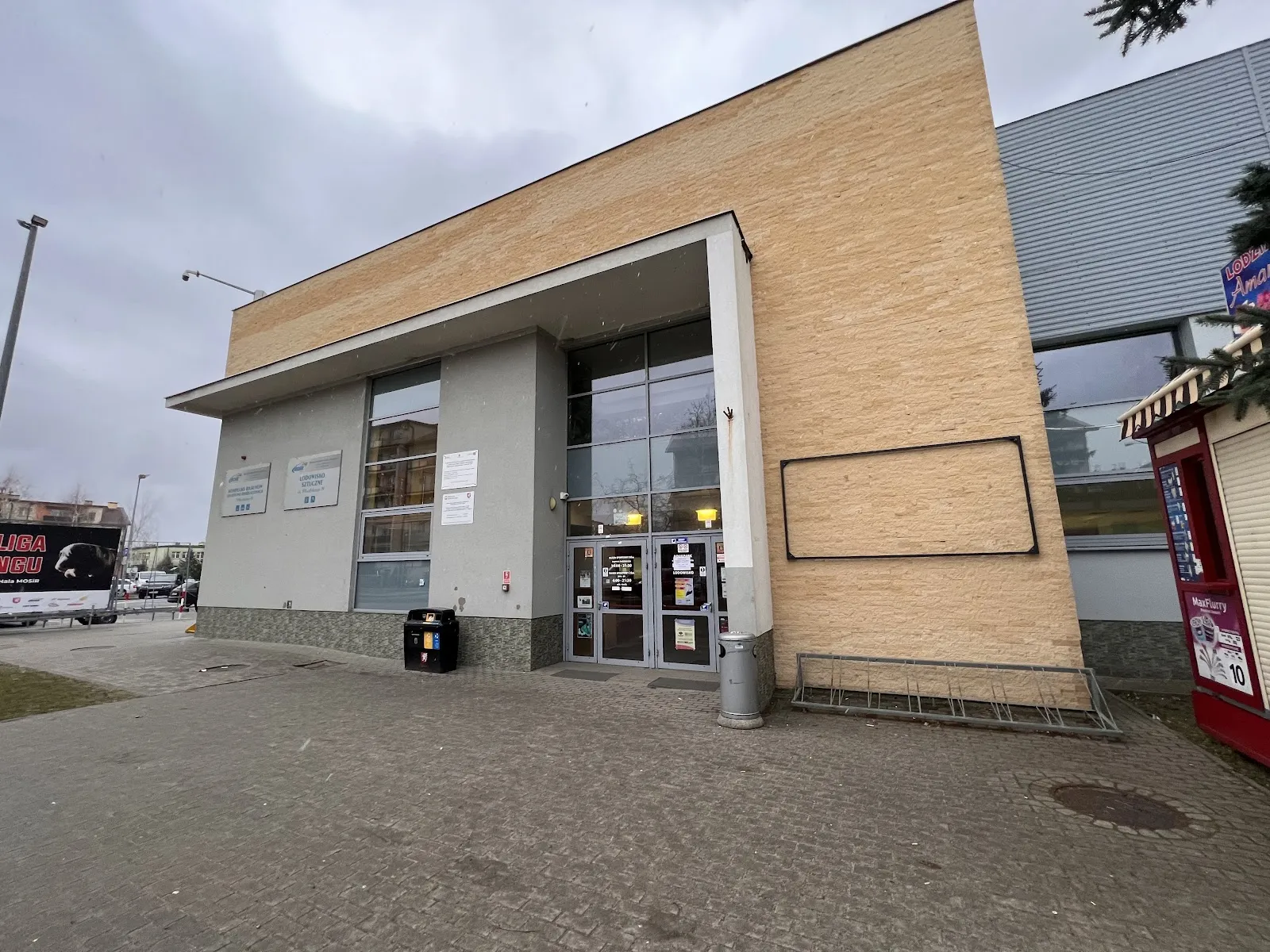 The glass-fronted entrance of the MOSiR ice hall in Dębica with its brick-clad front on Piłsudskiego street — Lodowisko MOSiR Dębica