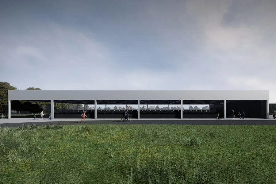 The low, flat-roofed Nowy Dwór rink building seen across the grass under a cloudy sky. — Lodowisko Nowy Dwór (WCT Spartan)