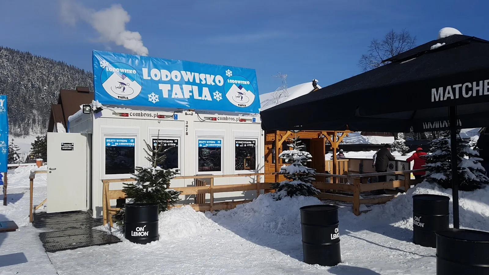 The ticket and skate-hire kiosk of Lodowisko Tafla in Zakopane with its banner, in the snow beside the rink — Lodowisko TAFLA (Zakopane)
