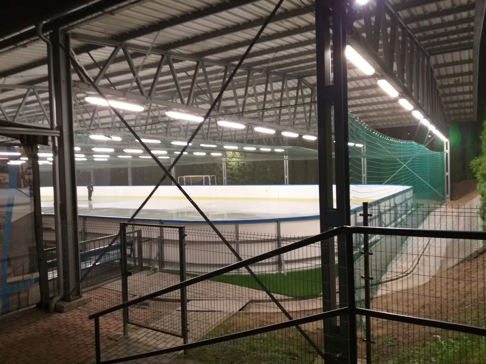 The roofed TOSiR ice rink on Wojska Polskiego street in Tarnów at night, seen from the stairs beside the boards under the lamps — Lodowisko zadaszone TOSiR Tarnów