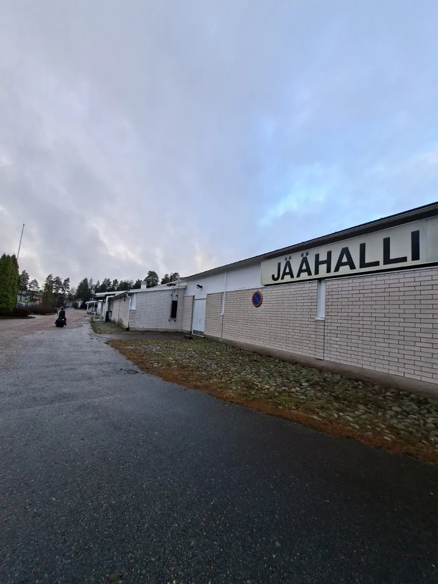 Tegelväggen på Lohjan jäähalli med skylten JÄÄHALLI ovanför, sedd från tillfartsvägen i skymningen. – Lohjan jäähalli