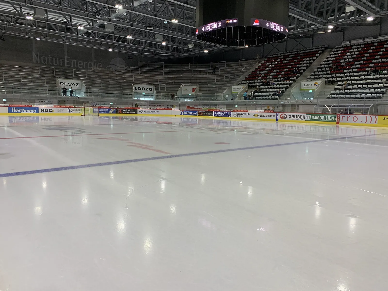 Die leere Eisfläche der Lonza Arena mit den Tribünen und dem Videowürfel dahinter – Lonza Arena